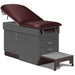 A medical examination table with drawers and patient step stool, burgundy upholstery and slate gray base color