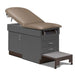 A medical examination table with drawers and patient step stool, warm gray upholstery and slate gray base color